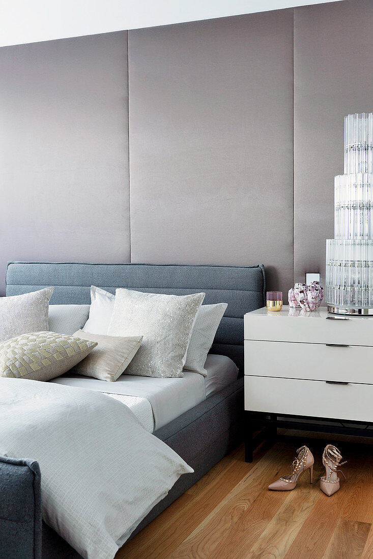 Gray upholstered bed against upholstered wall in glamorous bedroom