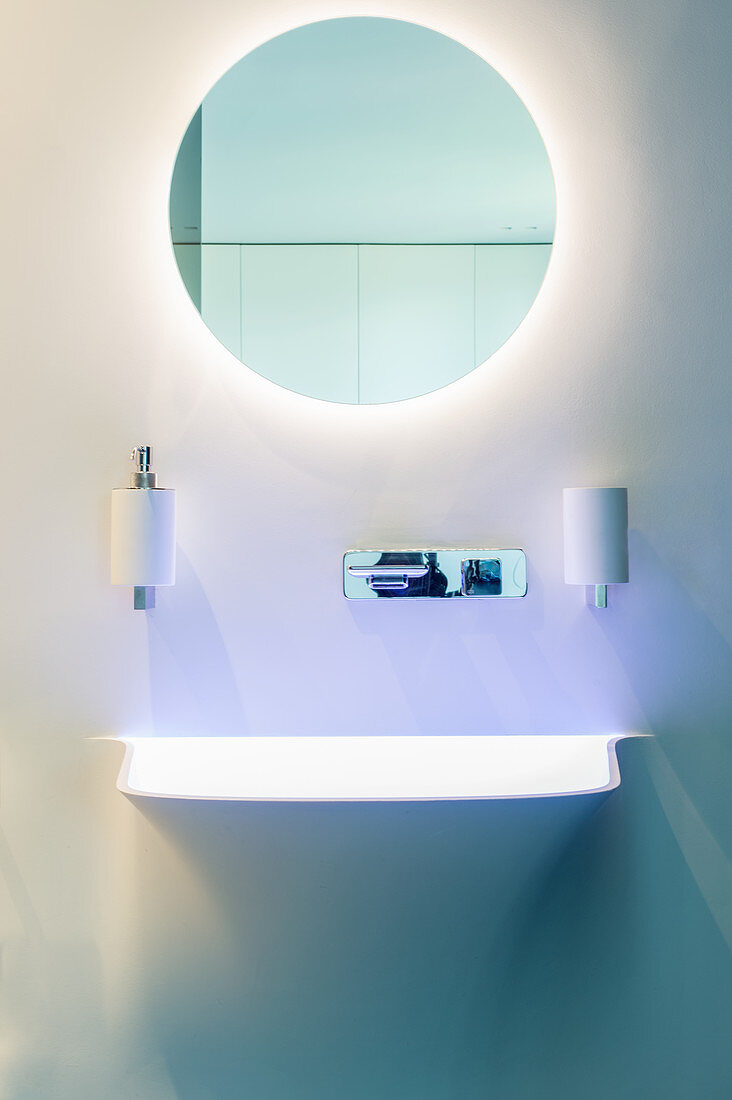 Designerbad mit rundem Spiegel und indirekter Beleuchtung