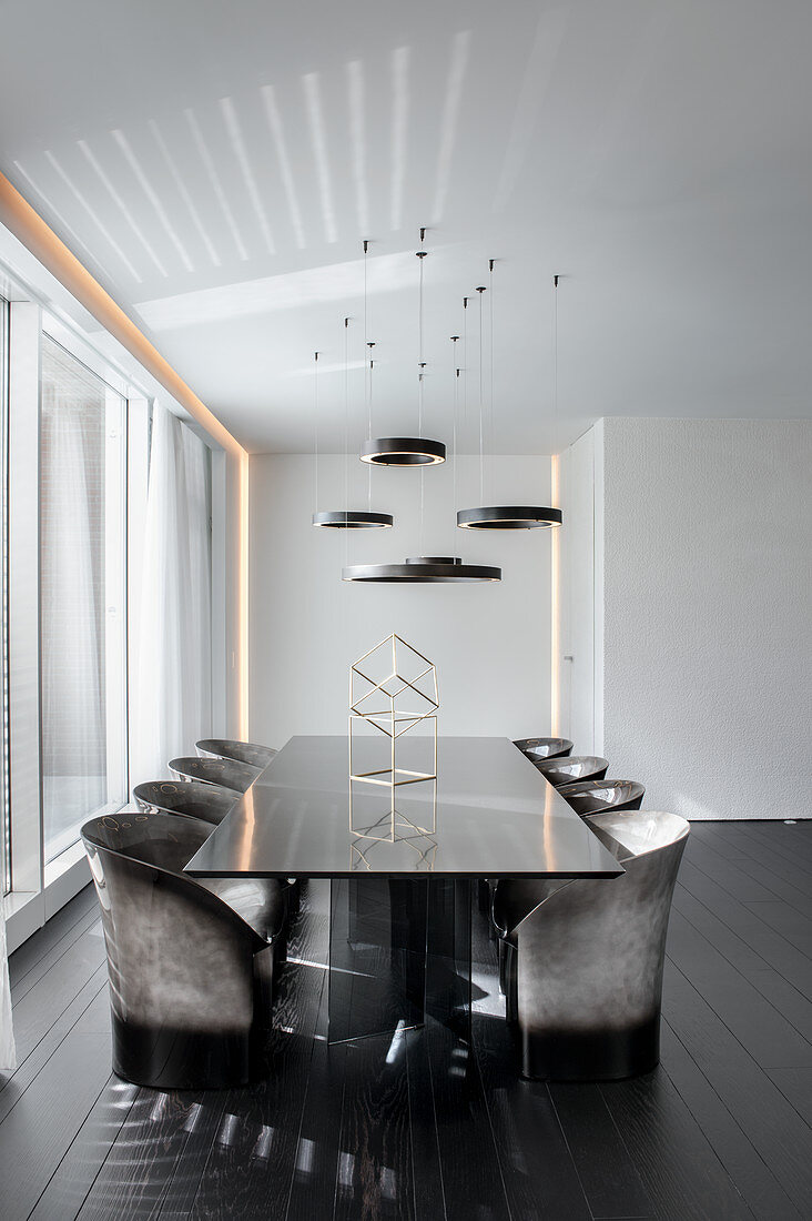 Elegant, black dining table with designer chairs in minimalist interior