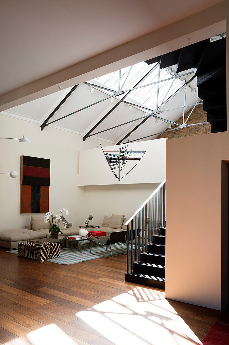 Spacious seating area in loft apartment with black, steel staircase leading to gallery