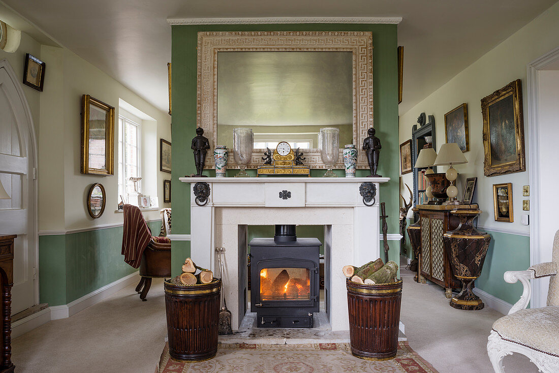 Antique mahogany turf buckets holding firewood in front of fireplace below large mirror