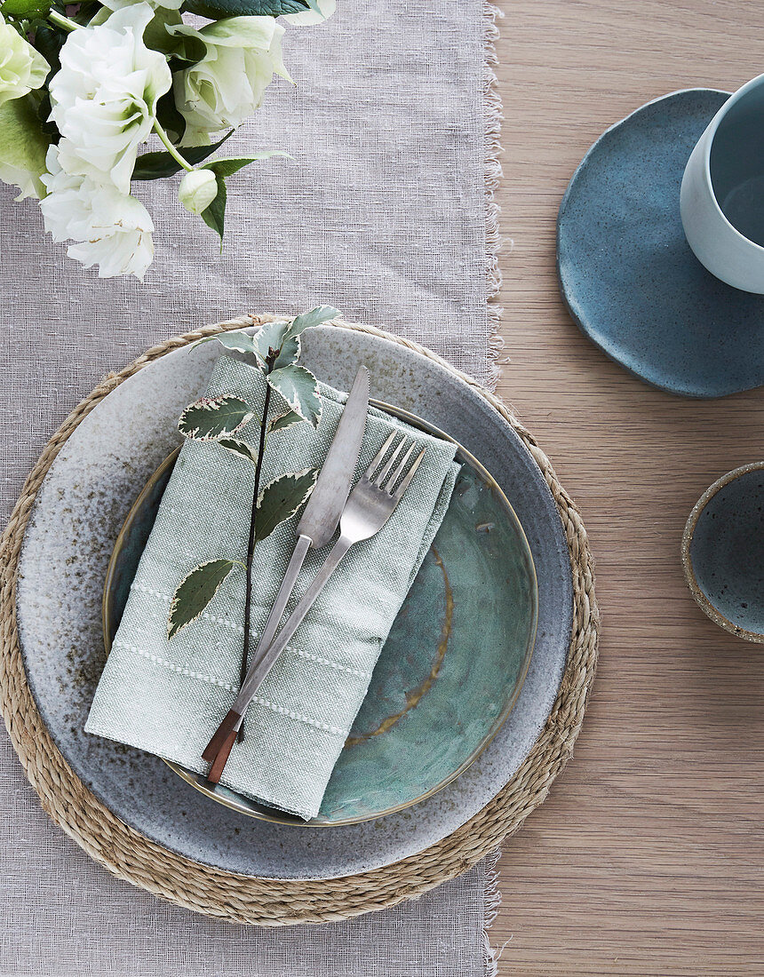 Place setting on linen tablecloth with cloth napkin and sprig of mint