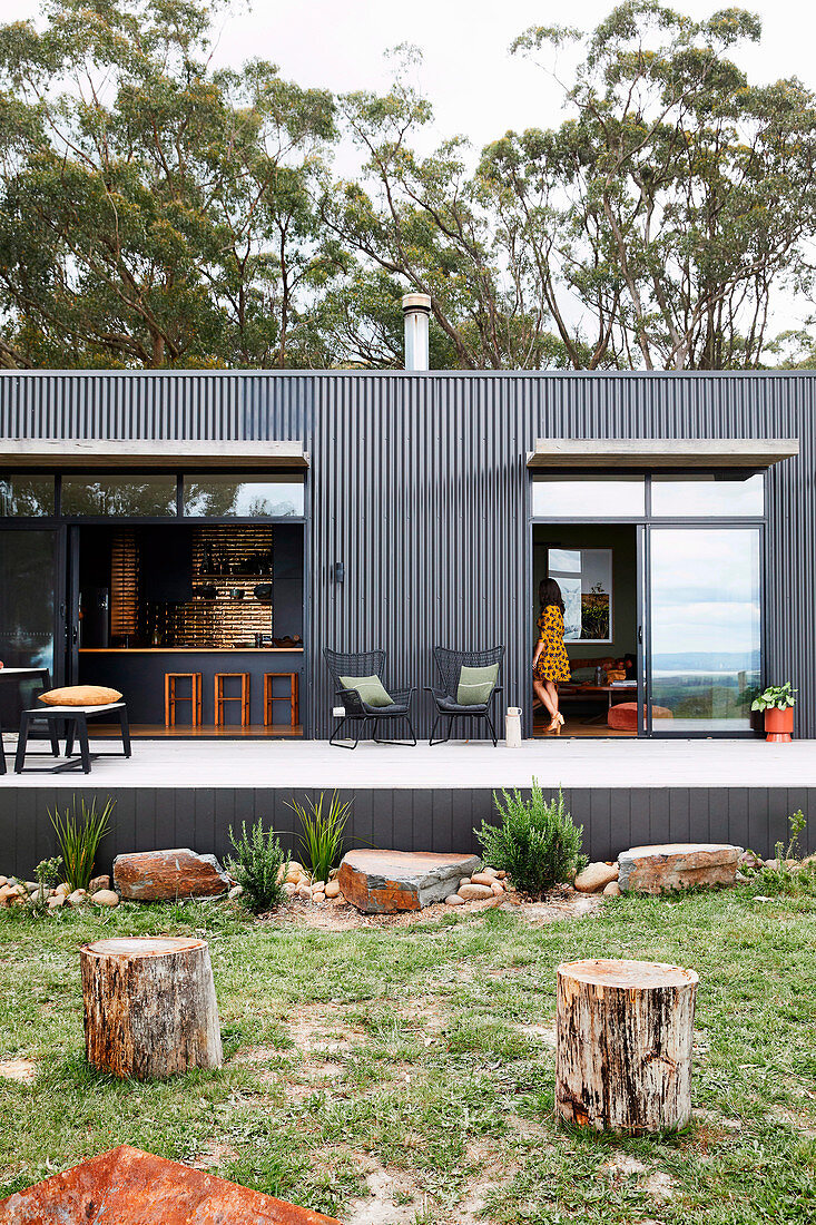 Modernes Haus aus grauem Wellblech mit Terrasse und Garten