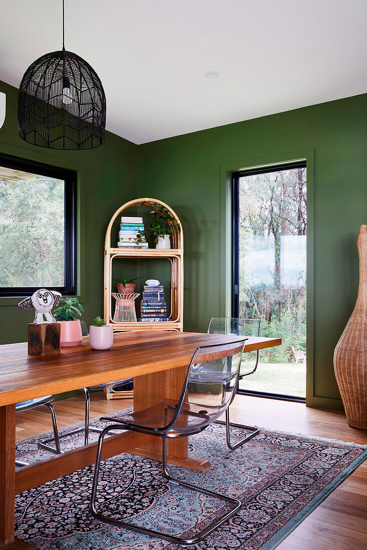 Kunststoff-Stühle am Holztisch im Esszimmer mit grünen Wänden
