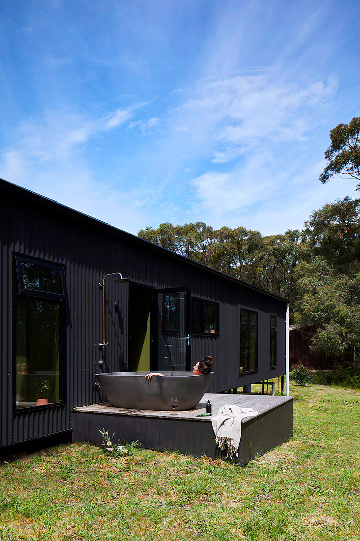 Bathtub on the terrace at the house with corrugated iron facade