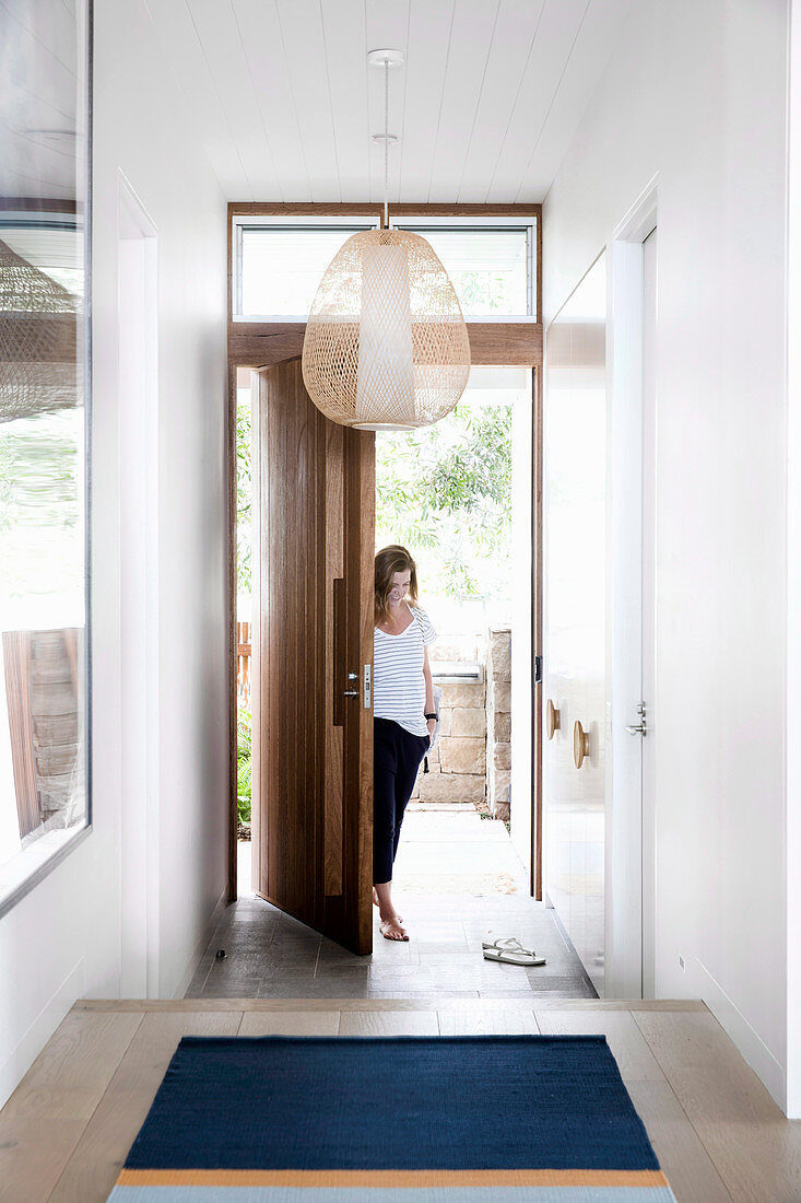 Woman enters the modern house through a pivoting front door