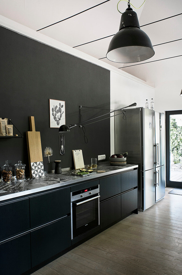 Küchenzeile mit schwarzen Schrankfronten und schwarzer Rückwand