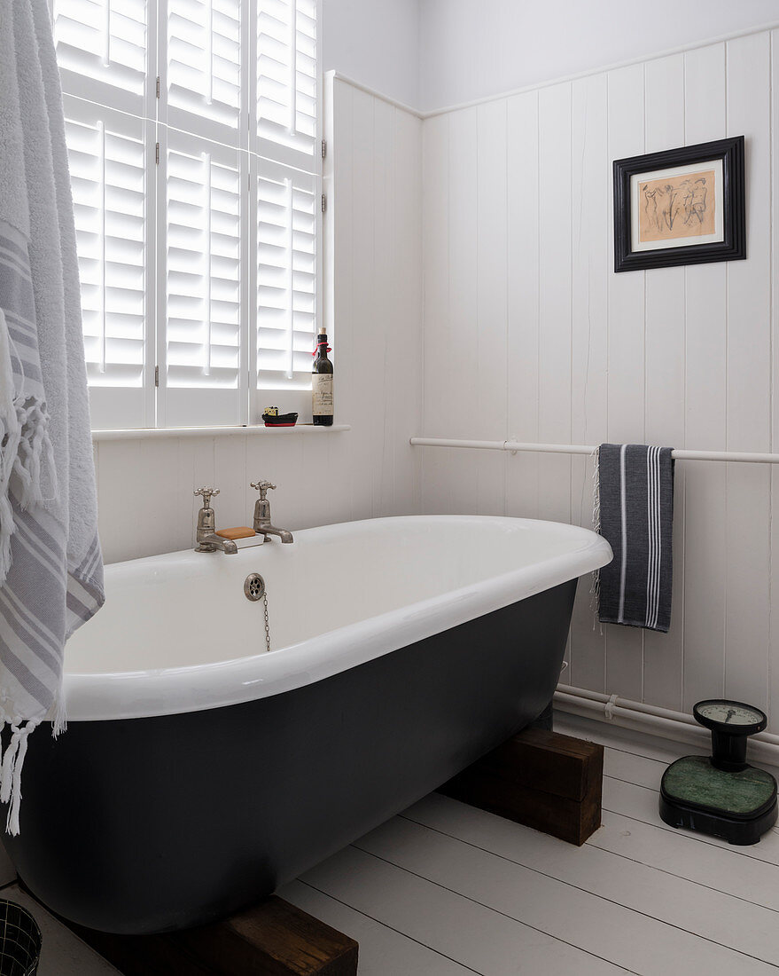 Freistehende Badewanne auf zwei Holzklötzen im klassischen Bad