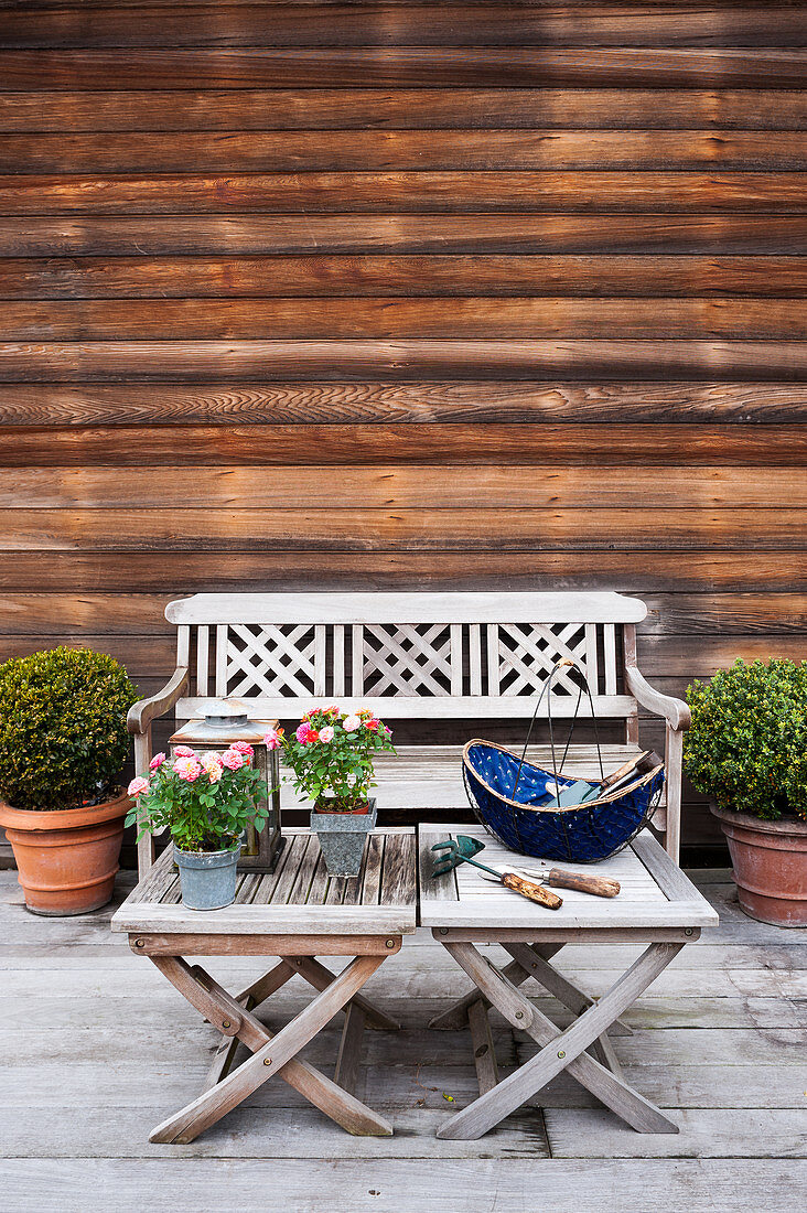 Sitzbank und Tische vor Holzfassade auf geräumiger Terrasse