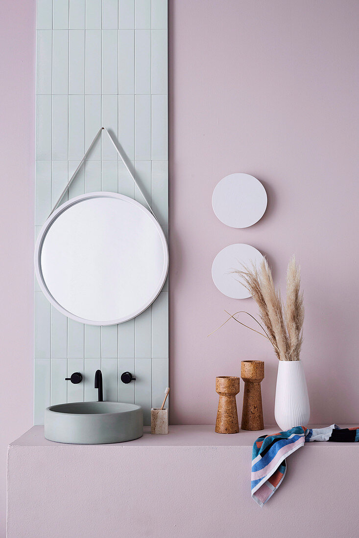Waschtisch mit Aufsatzbecken und runder Spiegel an pastellfarbener Wand