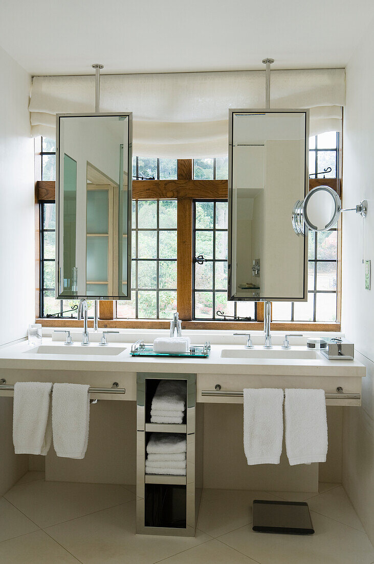 Cantilever limestone vanity area with pivoting mirrors