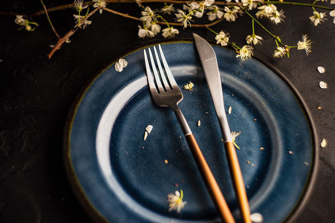 Tischgedeck mit blauem Teller und blühendem Pfirsichzweig