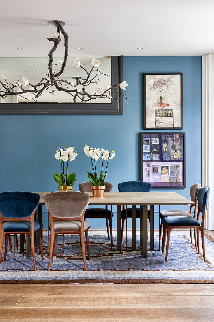 Magnolienleuchte über Esstisch mit Orchideen, Kunstwerke an blauer Wand