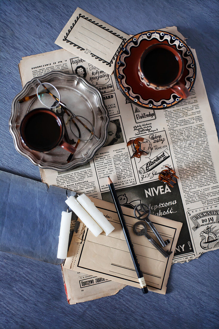 Alte Zeitung, Vintage Zinnteller, Kaffeetassen, Kerzen und Schlüssel