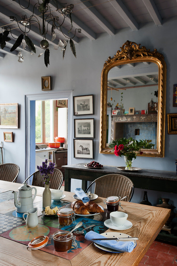 Antique mirror on blue wall and breakfast on table in dining room