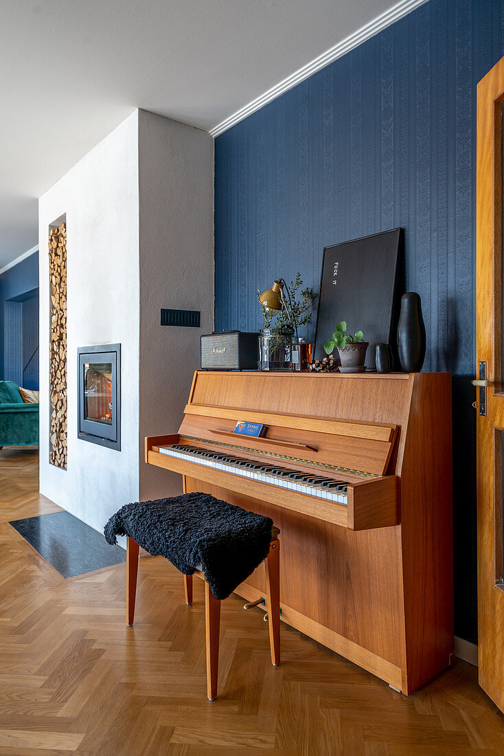 Klavier und Klavierhocker in offenem Wohnraum mit blauer Wand