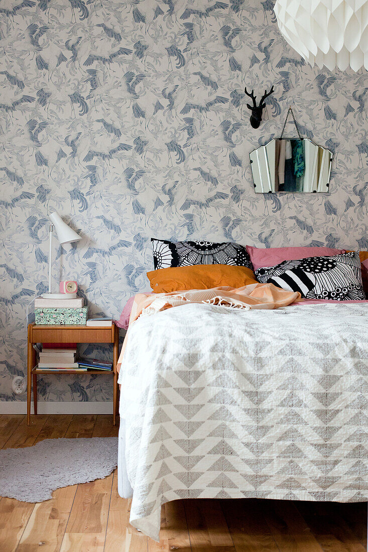 Bedspread with graphic pattern on bed against retro wallpaper