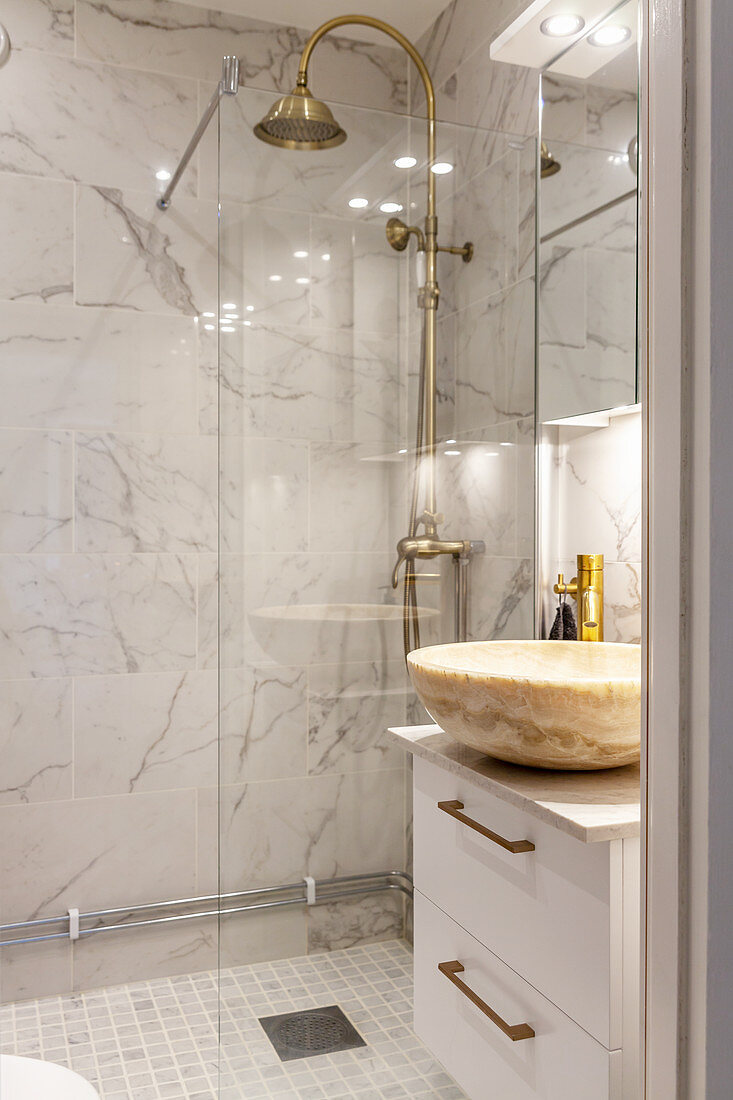 Elegantes Bad mit Marmor-Waschschale und verglaster Dusche mit Messingarmatur