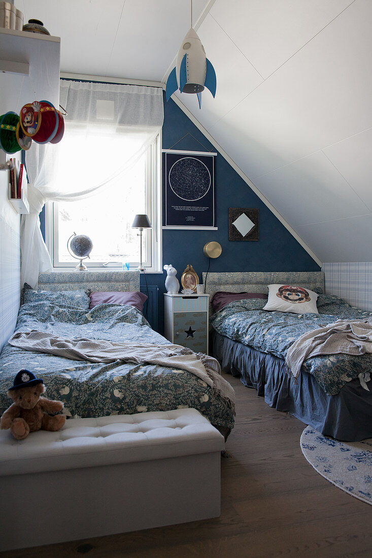Twin beds in vintage-style children's bedroom below sloping ceiling