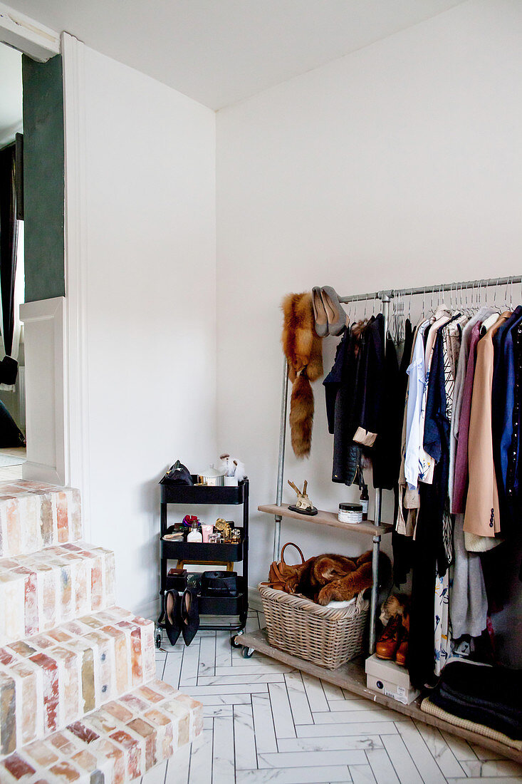Clothes rail in anteroom with herringbone floor and brick steps