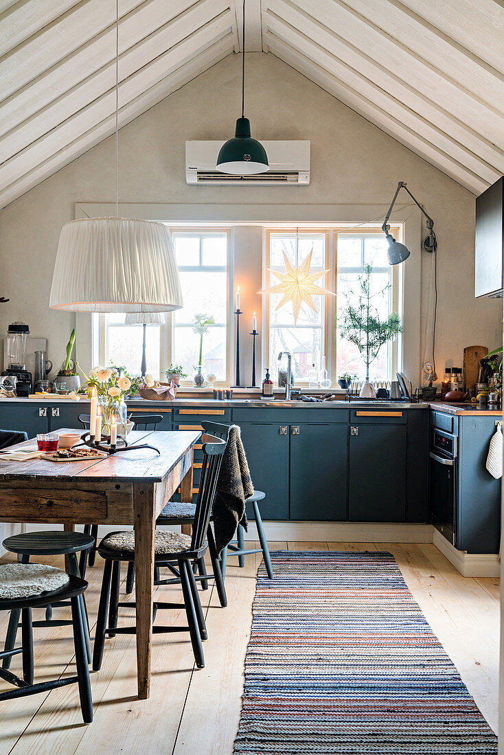 Blue cabinets and open roof structure in rustic kitchen-dining room