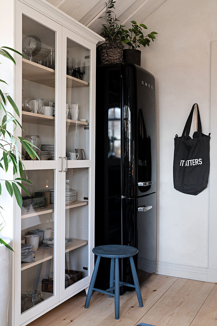 Blue stool in front of cupboard and black fridge