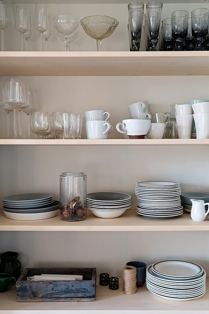 Glasses, cups and stacked plates on shelves