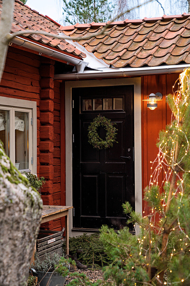 Schwarze Tür mit Kranz im winterlichen roten Schwedenhaus