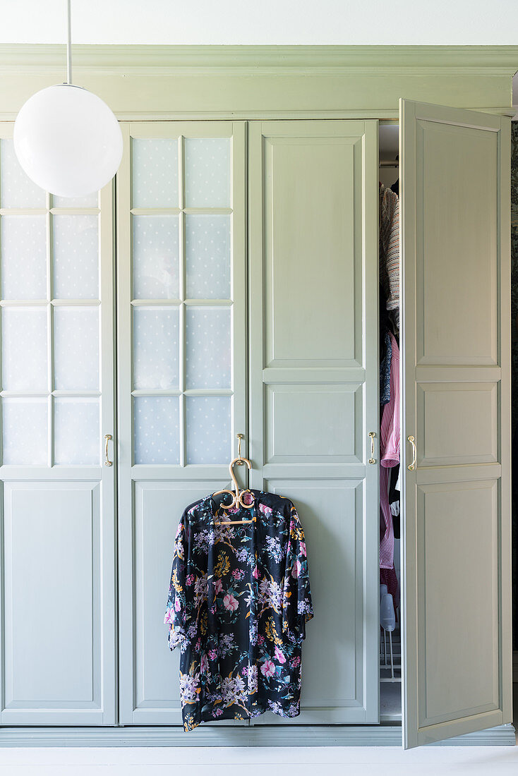 Floral kimono hanging from handle of wardrobe with panelled doors