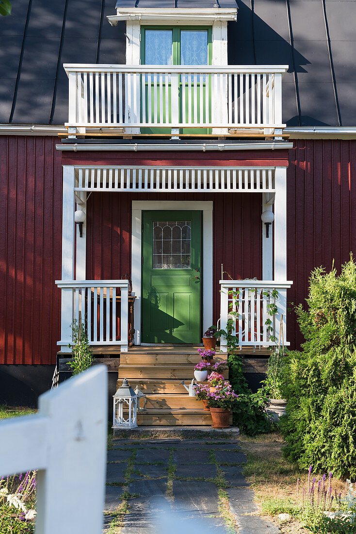 Grüne Haustür und Veranda eines roten Schwedenhauses