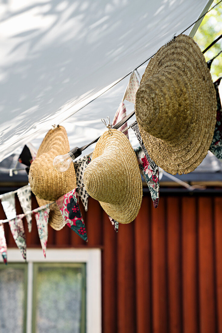 Straw hats hung from bunting below awning