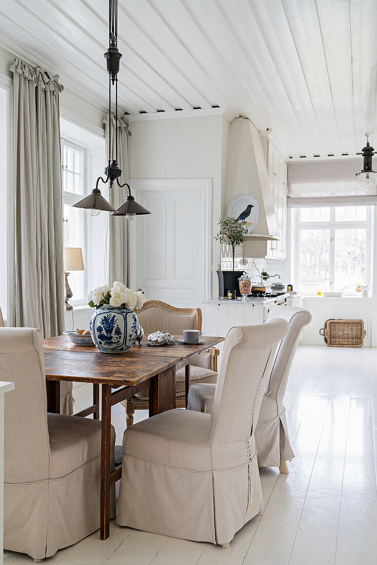 Loose-covered chairs and armchair in dining area with white wooden floor