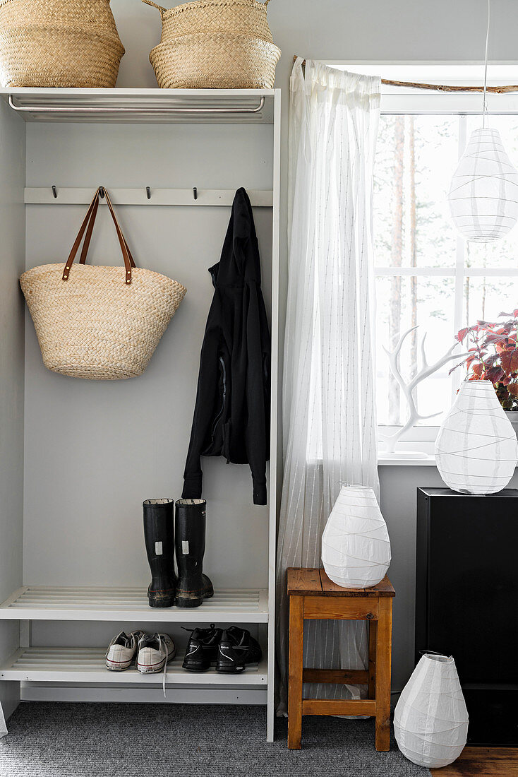 Baskets, row of pegs and shoe rack in grey cloakroom