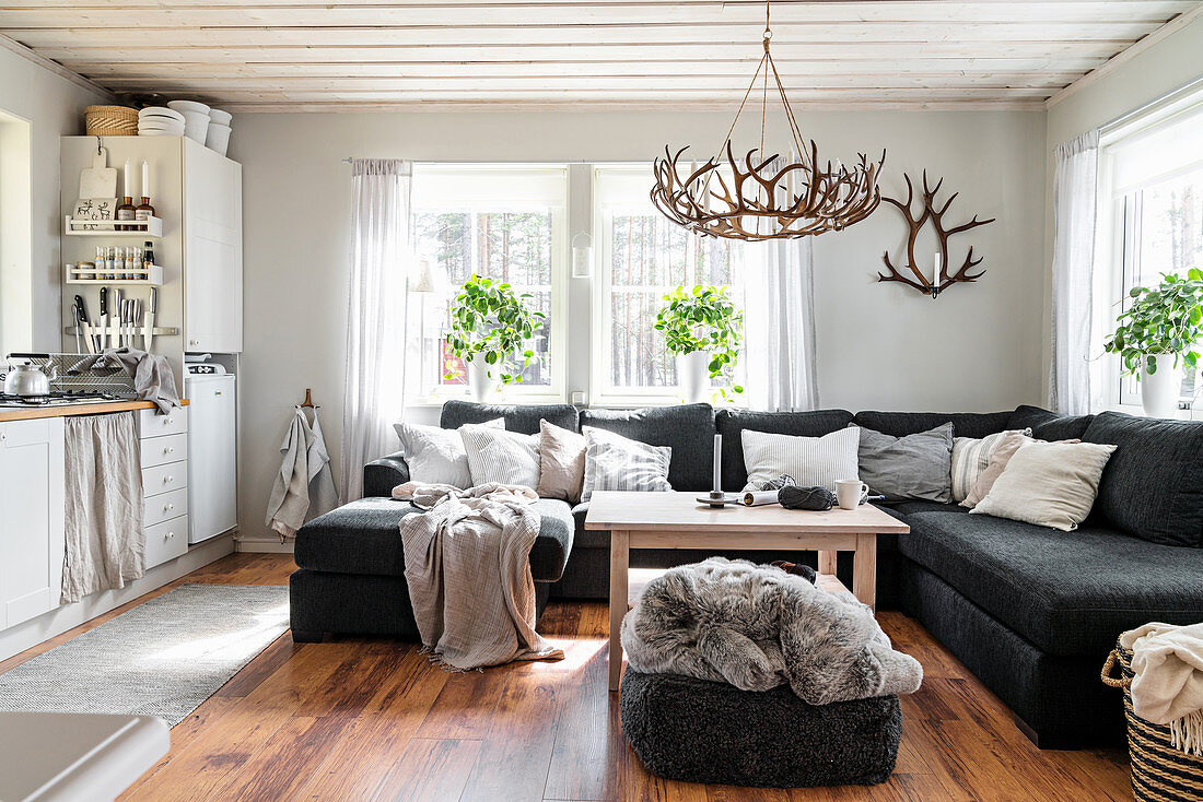 Dunkles Sofa im Wohnzimmer in Grautönen mit offener Küche