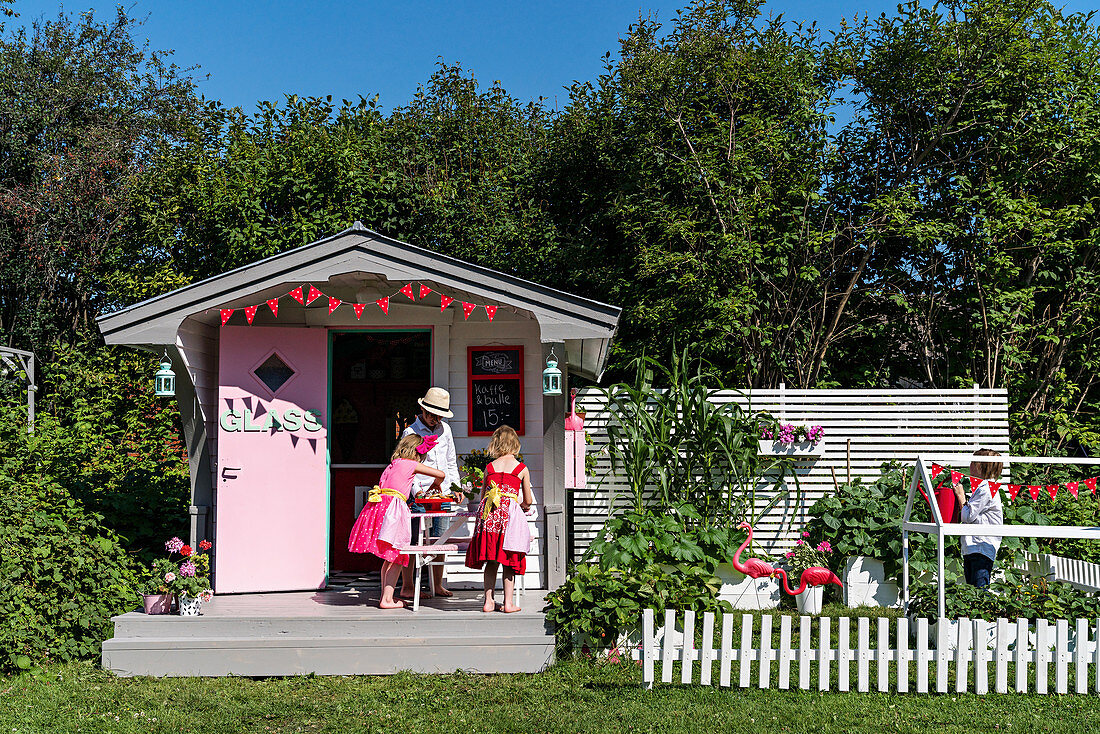 Spielhaus in amerikanischem Fifties-Style und spielende Kinder im Garten