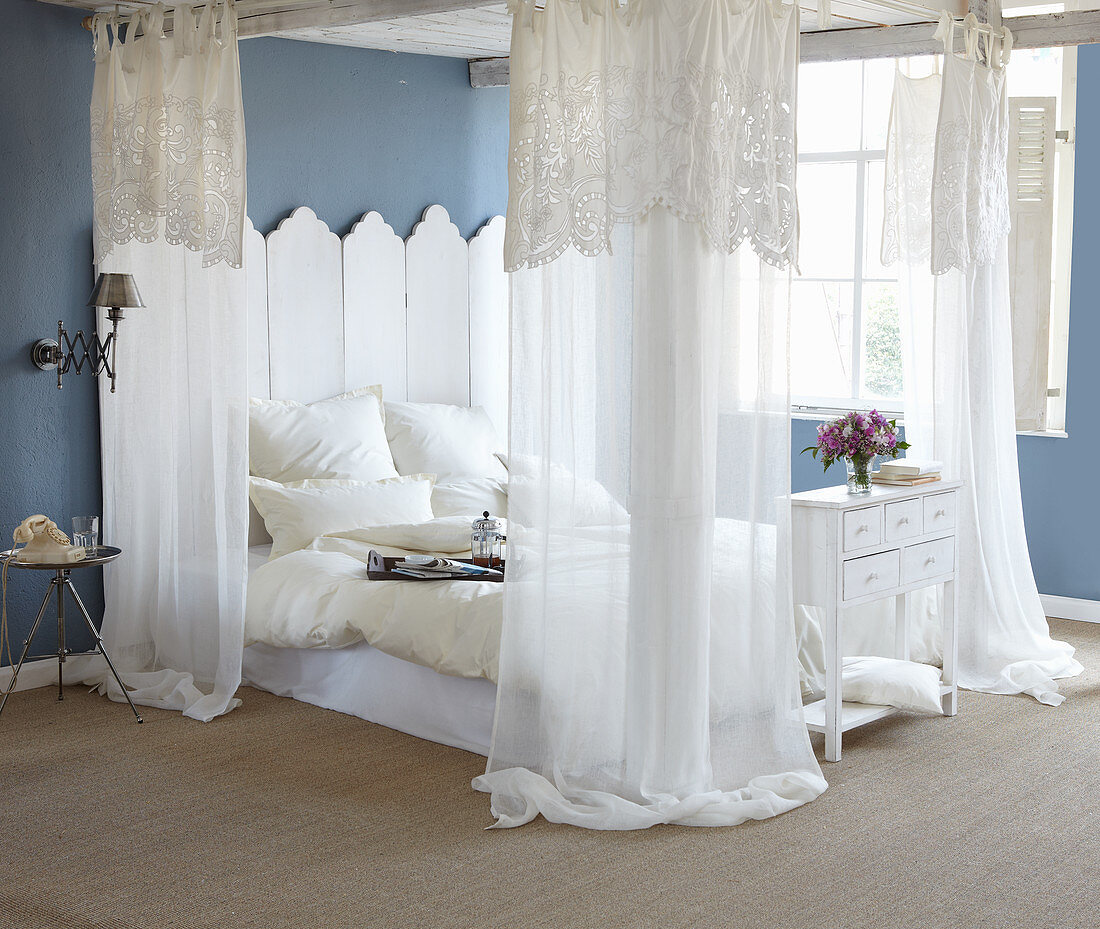 Romantisches Schlafzimmer mit blauen Wänden und Himmelbett