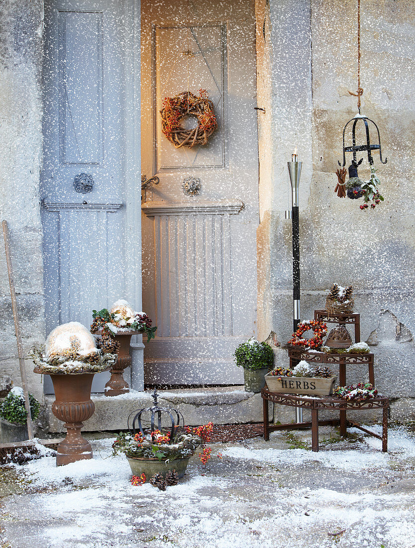Front door surrounded by wintry decorations dusted with snow