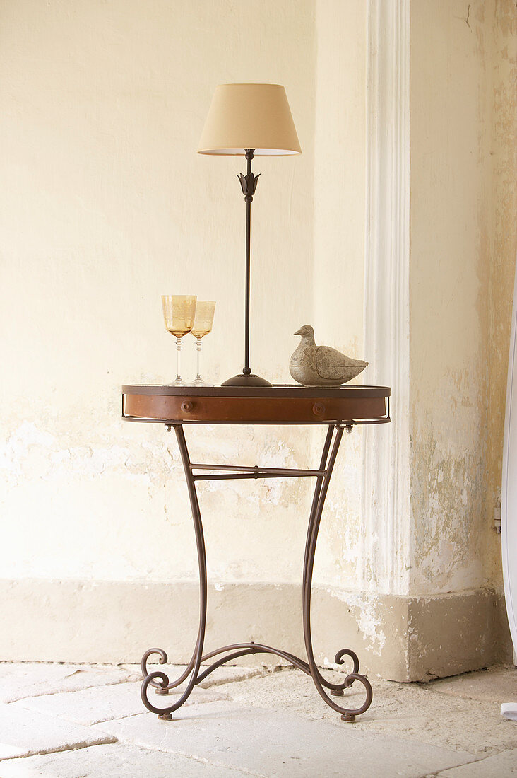 Side table with metal base in front of battered wall