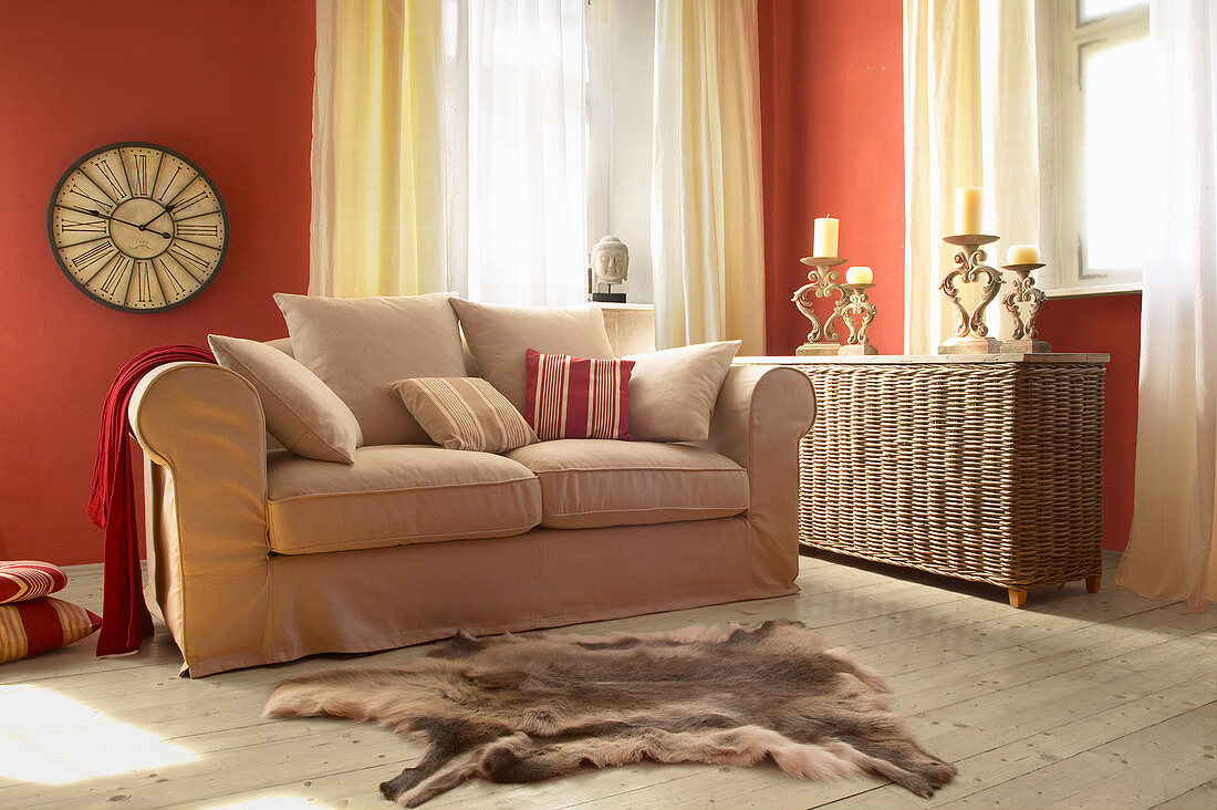 Beiges Sofa und Korbtruhe im Wohnzimmer mit roten Wänden