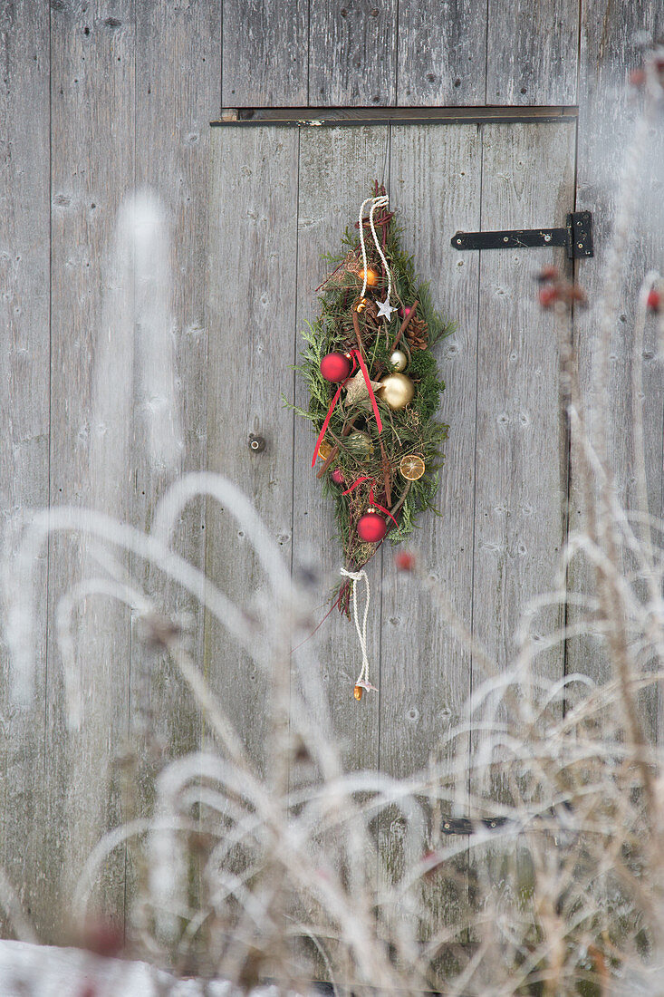 Weihnachtlicher Türkranz in Tropfenform aus Nadelzweigen und Kugeln