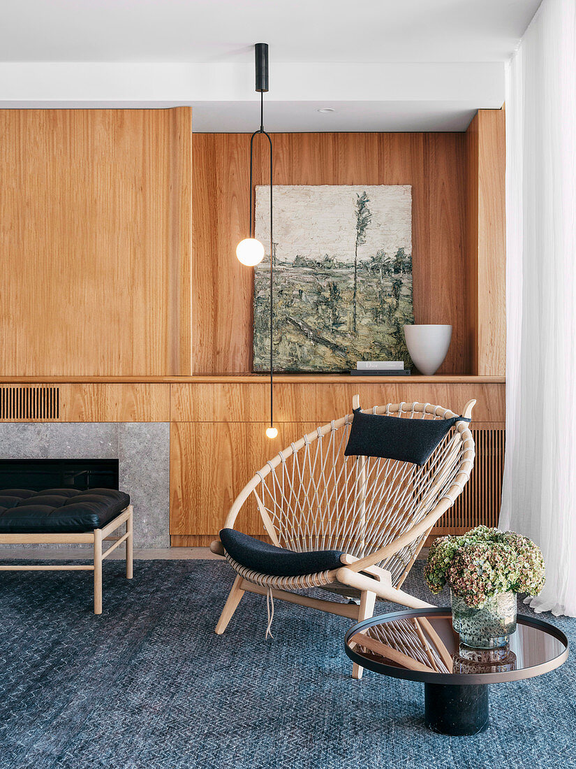 Runder Makramee-Sessel vor der Wohnwand aus Holz