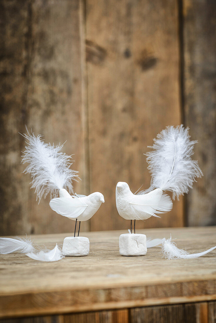Two bird figurines handmade from modelling clay and feathers