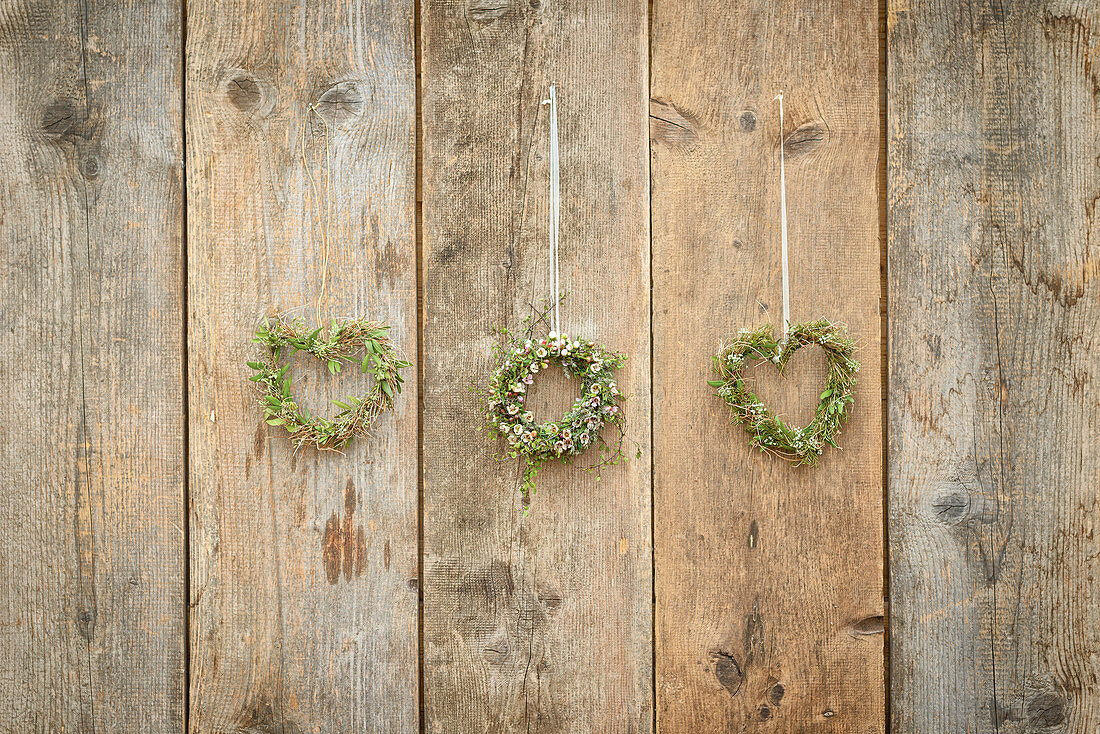 Round and heart-shaped wreaths on rustic board wall