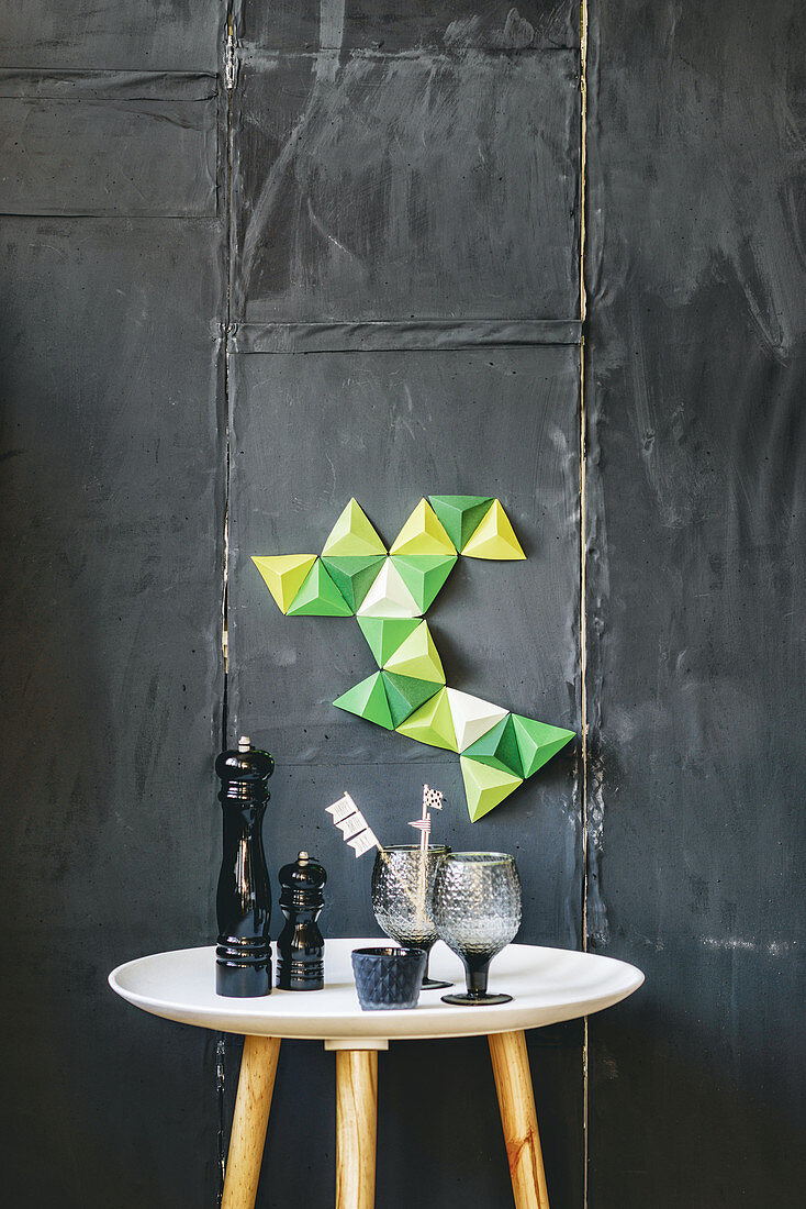 Deko aus grünen Papier-Pyramiden an schwarzer Wand