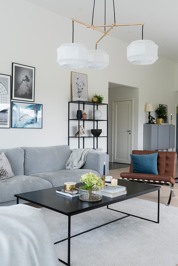 Wohnraum in Grau-Weiiß mit Sofa, Ledersessel und Designerleuchte über Couchtisch