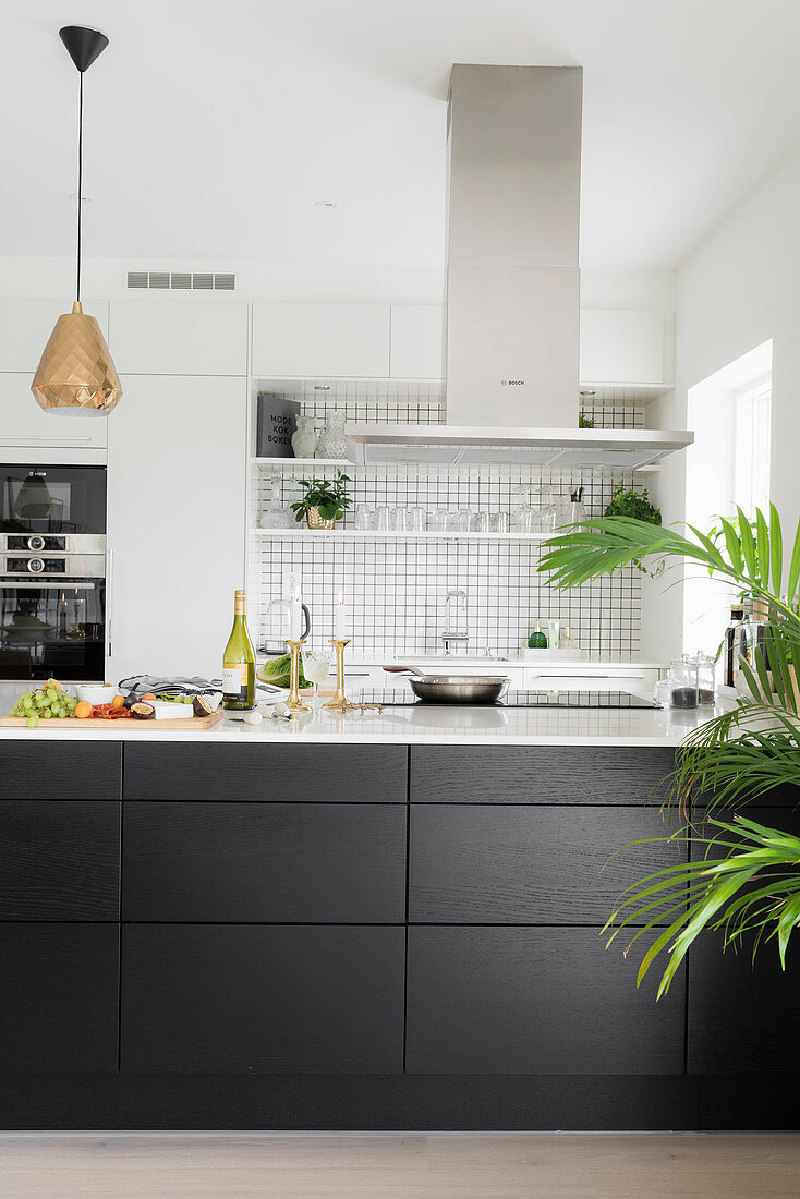 White wall units and black counter in open-plan kitchen