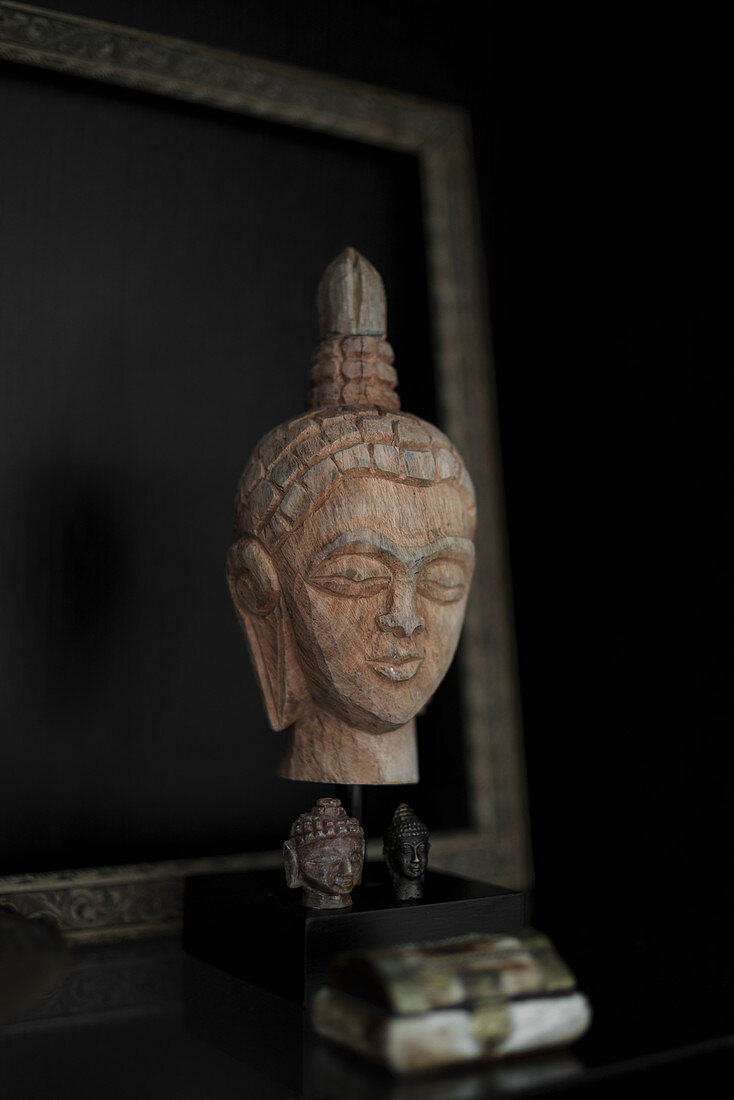 Wooden head of the Buddha against black background