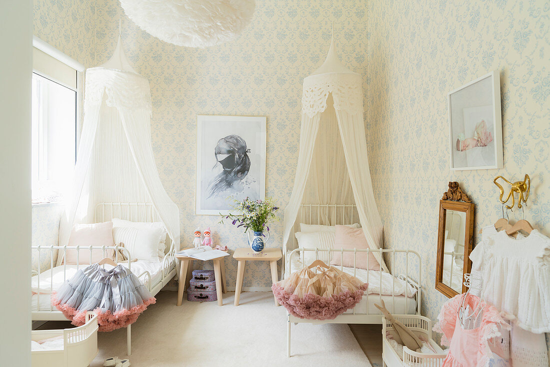 Canopied beds and pastel wallpaper in siblings' bedroom