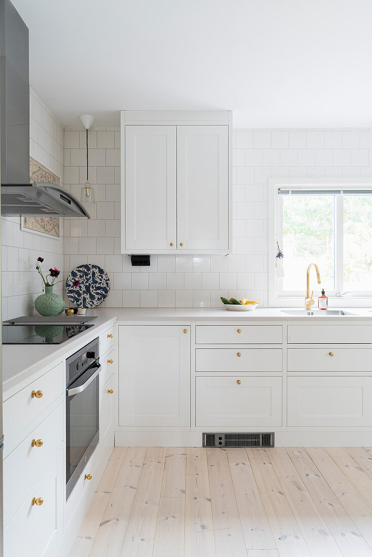 Classic kitchen with white panelled cupboards and golden handles