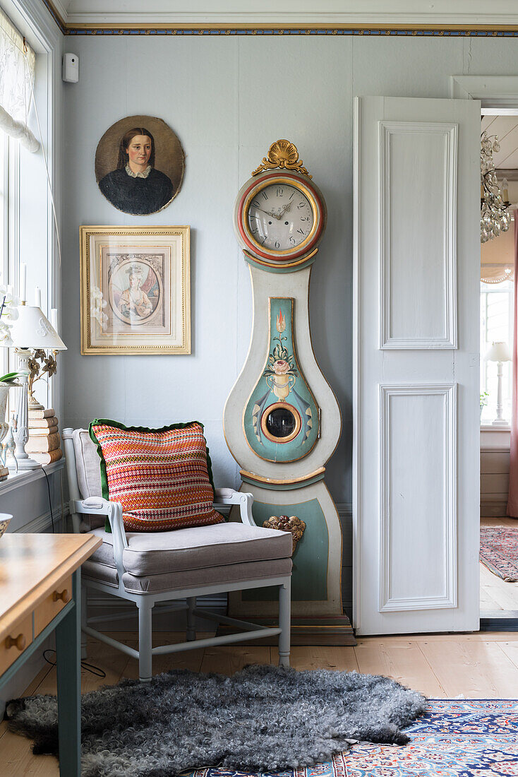 Armchair, antique longcase clock and open double doors in Swedish house